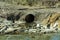 A big pipe in the river. Factories and plants dump harmful substances and waste into reservoirs. Environmental pollution.