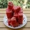 Big plate of pink juicy cubical watermelon pieces on garden table