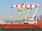 Big port crane loading steel coil in a cargo ship