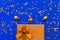 Big present box with  bow on a colorful background with sequins and decorative golden balls