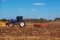 Big purple tractor plows the field and removes the remains of previously mown sunflower.