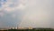 Big rainbow above city buildings. Time lapse.