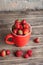 Big red cup filled with succulent juicy fresh ripe red strawberries on an old wooden textured table top with brick background