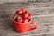 Big red cup filled with succulent juicy fresh ripe red strawberries on an old wooden textured table top with brick background