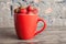 Big red cup filled with succulent juicy fresh ripe red strawberries on an old wooden textured table top with brick background