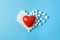 Big red heart on broken heart made of sugar cubes on a blue background