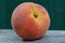 Big red ripe peach lies on a gray table