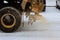 Big red snowplow sands carriageway during snowfall and ice