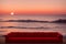 Big red sofa on shore of ocean, sea at sunset. Comfortable couch on sandy beach. Generative AI.