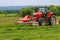 Big red tractor with two mowers mows the grass for silage