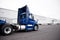 Big rig day cab blue semi truck driving to warehouse dock for pi