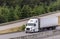 Big rig long haul semi truck transporting food in refrigerated semi trailer running on the multiline highway with exit road