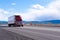 Big rig red semi truck with refrigerated semi trailer transporting commercial cargo on flat road in Utah