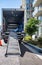 Big rig semi truck with open box trailer stands on the street near an apartment building with a lowered gangway and equipment for