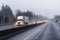 Big rig semi truck with semi trailer running with turned on headlights on wet raining highway with another cars traffic in evening