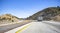 Big rig semi truck transporting frozen cargo in refrigerated semi trailer driving on the winding highway road between Shasta hills