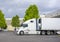 Big rig semi trucks with refrigerator semi trailer loading frozen cargo standing at warehouse dock gates