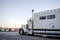 Big rig white powerful semi truck with comfort long sleeping compartment standing on truck stop for take a break in the route