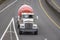 Big rig white semi truck with concrete mixer tank running on the wide divided highway