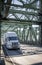 Big rig white semi truck with grille guard carry cargo in dry van semi trailer running on the arched sectional truss bridge