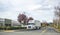 Big rig white semi truck with refrigerator semi trailer standing on the road near warehouse parking lot