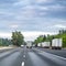 Big rigs semi trucks with different loaded semi trailers standing in a line by the side of the highway road for a break outside of