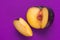 Big ripe organic purple plum with cut out segment wedge on vivid ultra violet background. Yellow flesh pit close up. Creative