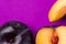 Big ripe organic purple plum whole with cut out segment wedge vivid violet background. Yellow flesh pit close up. Creative trendy