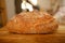 Big round appetizing fresh wholemeal bread with bran on wooden board, wheat, rye, multigrain bread, illuminated rays sun, concept