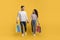 Big Sales. Happy Arab Couple Walking With Shopping Bags On Yellow Background