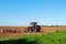 Big silver tractor with a red harrow disc cultivator in the field on a sunny day. The concept of work in a fields and agriculture