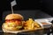 Big single chickenburger with french fries isolated on black background. hamburger with chicken patty , onion, tomato, lettuce