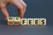 Big or small fees symbol. Businessman turns a wooden cube and changes words `small fees` to `big fees`. Beautiful grey table,