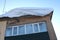 Big snow drift dangerously hanging over the window falls from the roof of the house