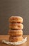 A big stack of sugar coated doughnuts on crumpled paper, on wooden background