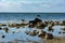 Big stones on a coast in the sea, with sailing ship on the horizon