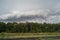 Big storm cloud flying out from behind the forest