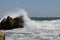 Big storm waves hitting the coastal rocks of the sea. Sunny windy day, blue sky. Splashes and foam. Storm landscape.