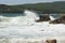 Big storm waves hitting the coastal rocks of the sea. Sunny windy day, blue sky. Splashes and foam. Storm landscape.