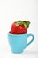 Big strawberry in blue espresso cup over white