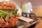 Big tasty burger with ham against defocused cafe interior