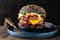 Big tasty hamburger with black bun and double beef cutlet in a blue plate