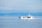 Big tourist boat sails on sea water against large mountains