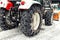 Big tractor machine with steel metal chains driving through slippery icy road or city street at alpine mountain region in winter