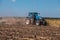 Big tractor plows the field and removes the remains of previously mown sunflower.