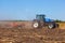 Big tractor plows the field and removes the remains of previously mown sunflower.