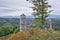 Big tree and stone lookout on top of Bucina hill with Ohre river valley and Ore mountains on background at beginning autumn czech