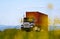 Big truck with container view through yellow flowers