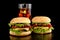Big two cheeseburgers with glass of cola on black wooden table