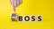 Big vs small boss symbol. Businessman hand points at wooden cubes with words Small boss and Big boss. Beautiful yellow background